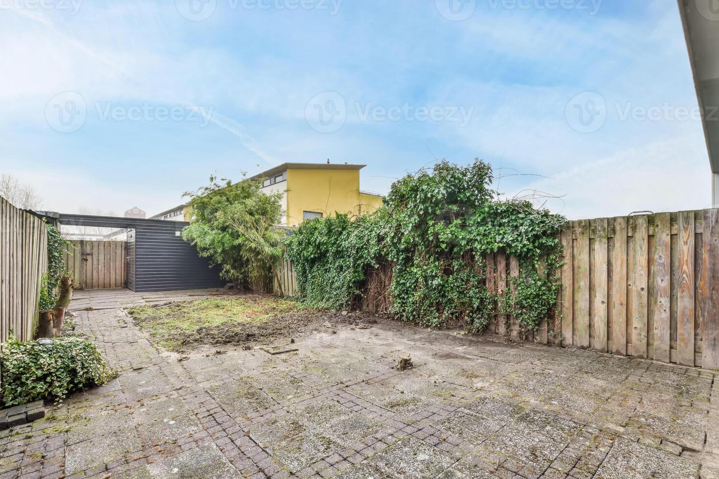 A backyard with a fence and a brick patio photo