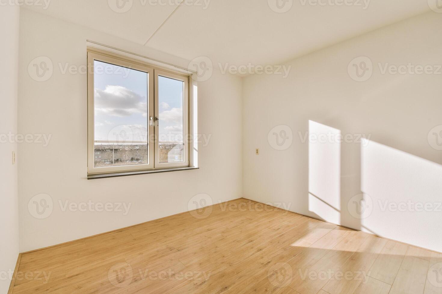 An empty room with a window and wooden floors photo