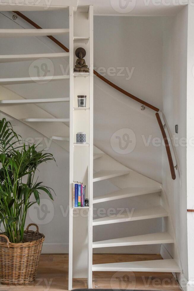 A white staircase with a bookcase and a plant photo