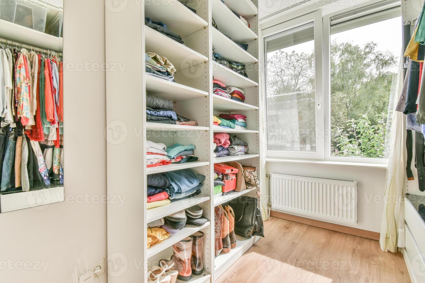 A walk - in closet with clothes and shoes photo