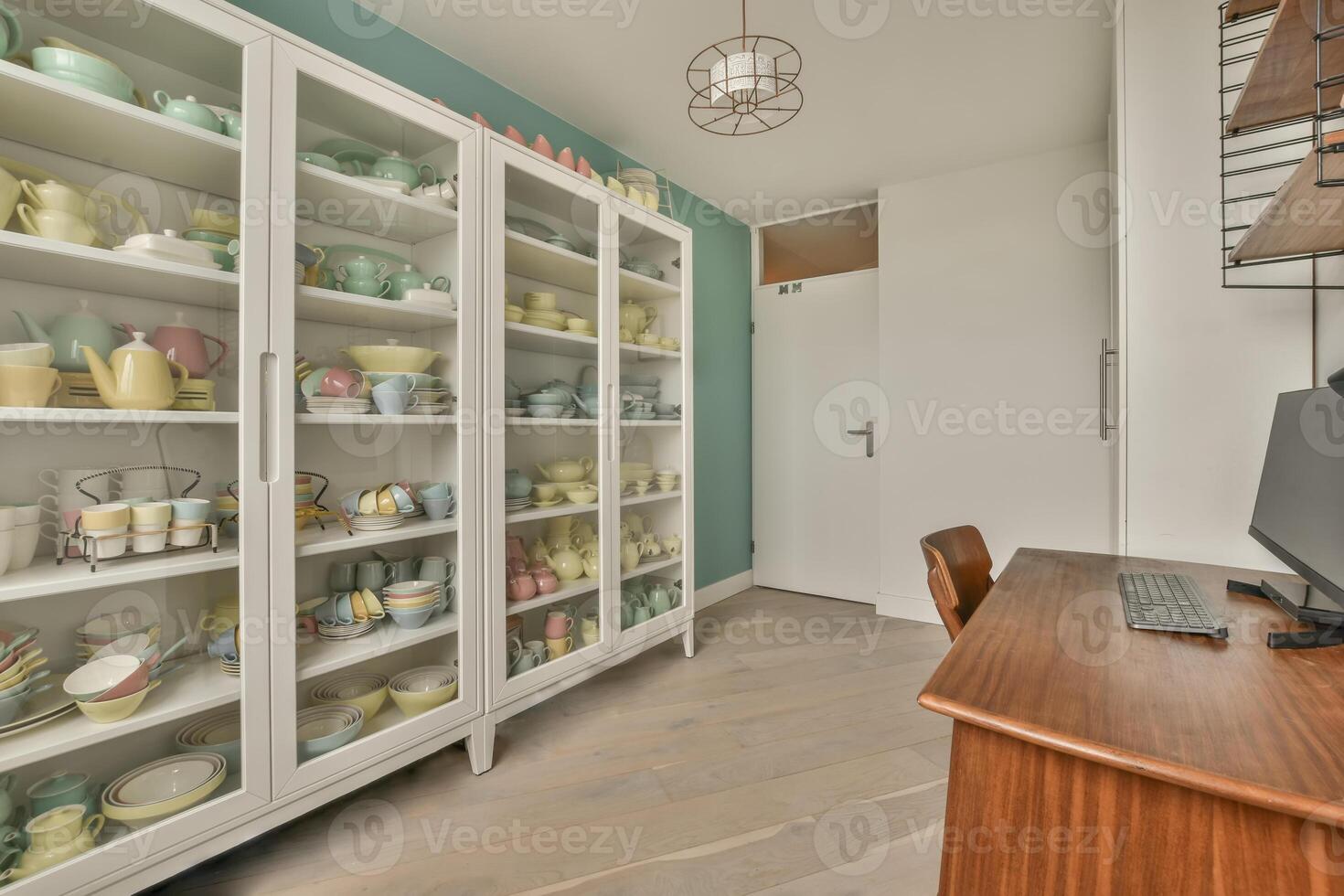A room with a desk and a cabinet full of dishes photo