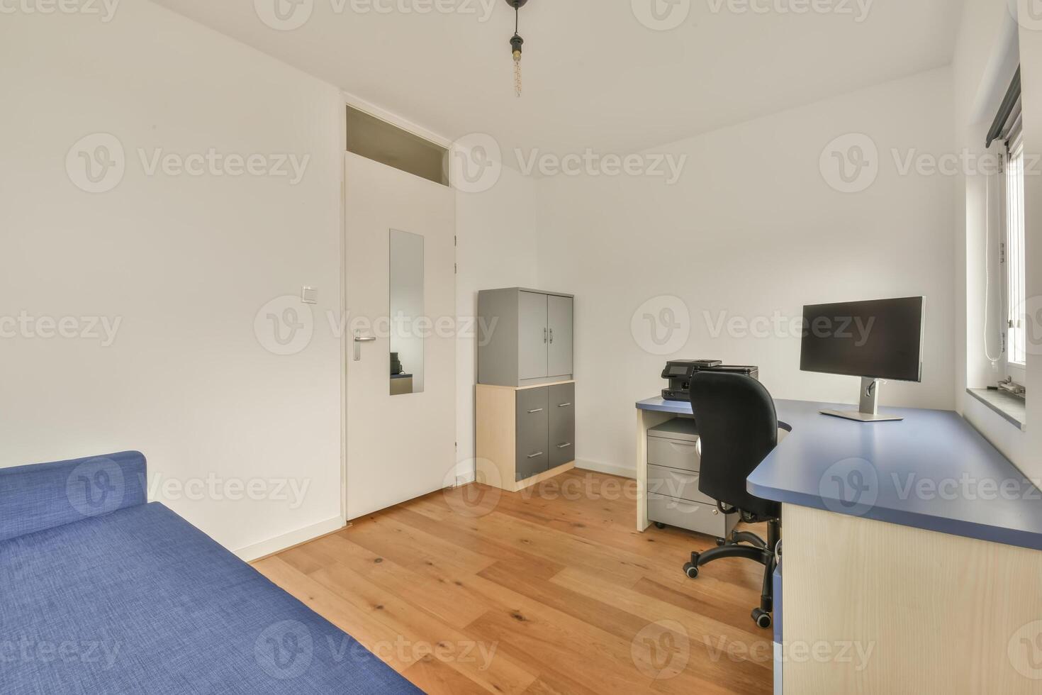 A small room with a desk, chair and a computer photo