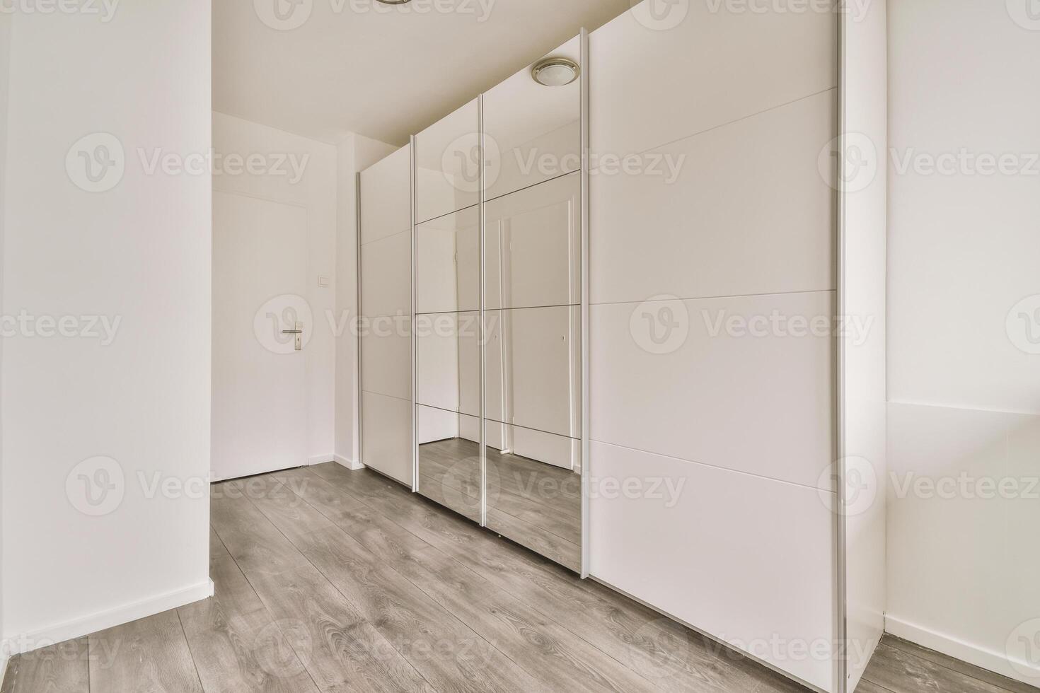 A white closet with mirrored doors and wooden floors photo