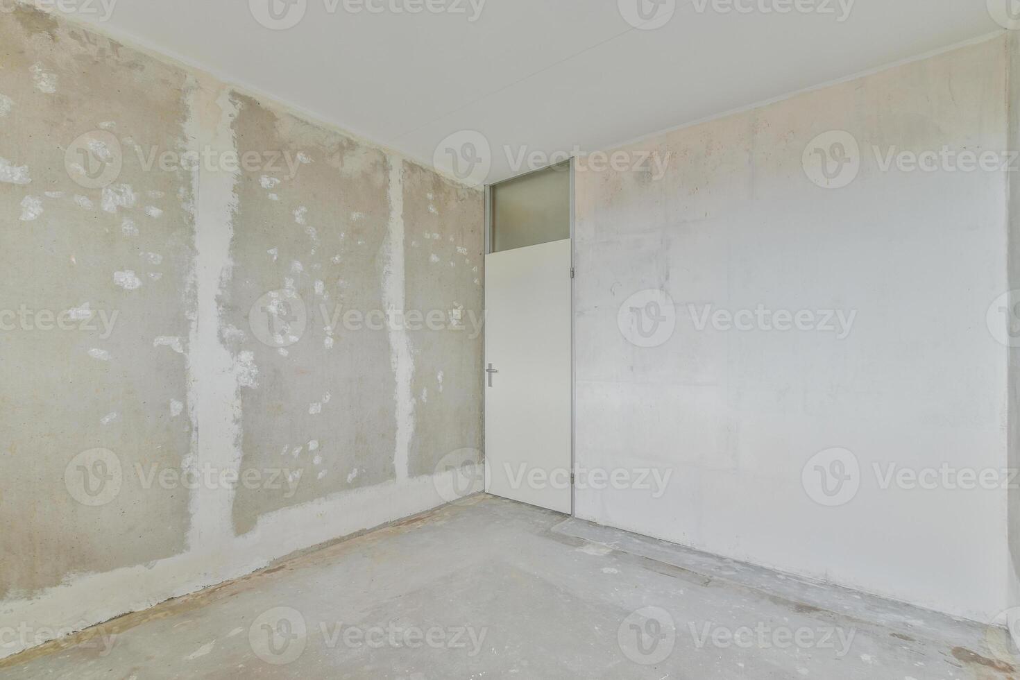 A room with a white door and a wall covered in drywall photo
