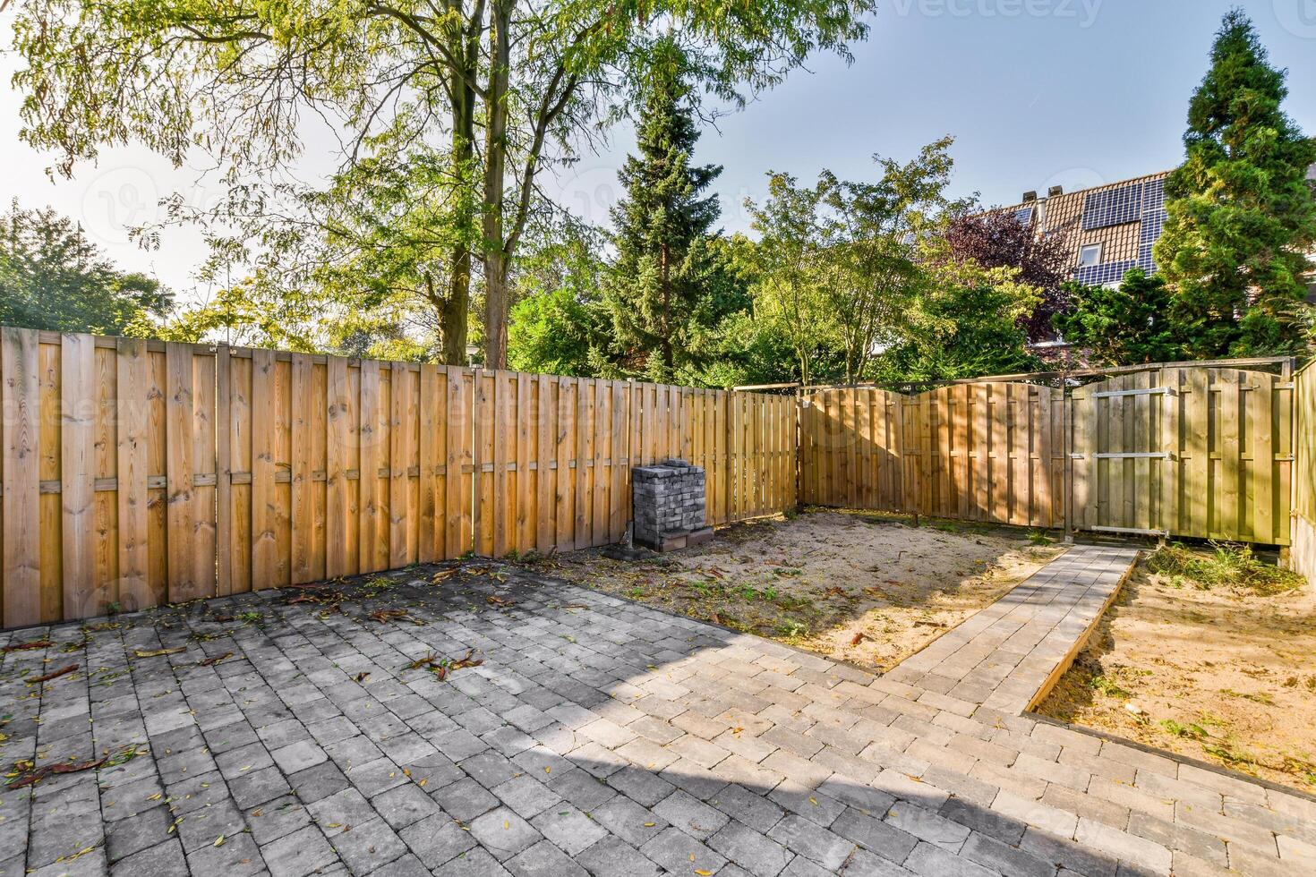 A backyard with a brick patio and wooden fence photo