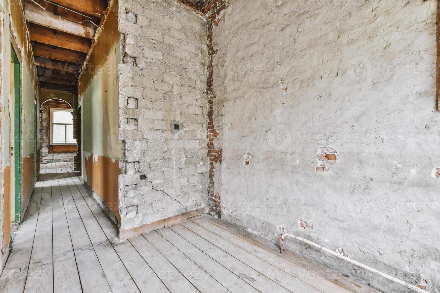 An empty room with a wooden floor and a brick wall photo