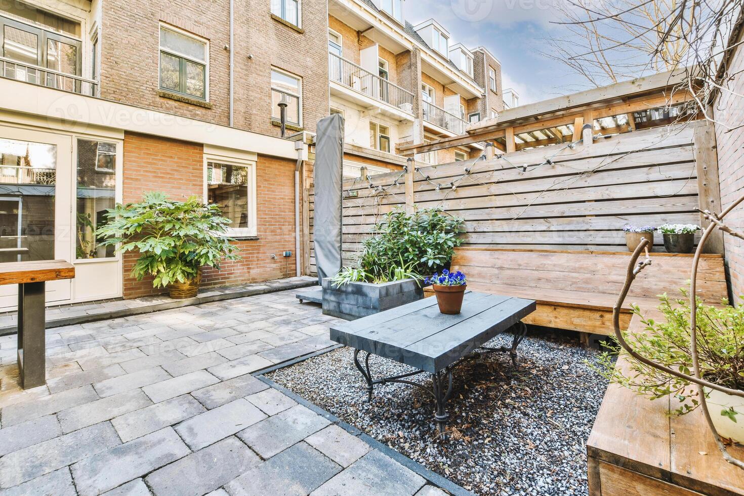A patio with a wooden bench and potted plants photo