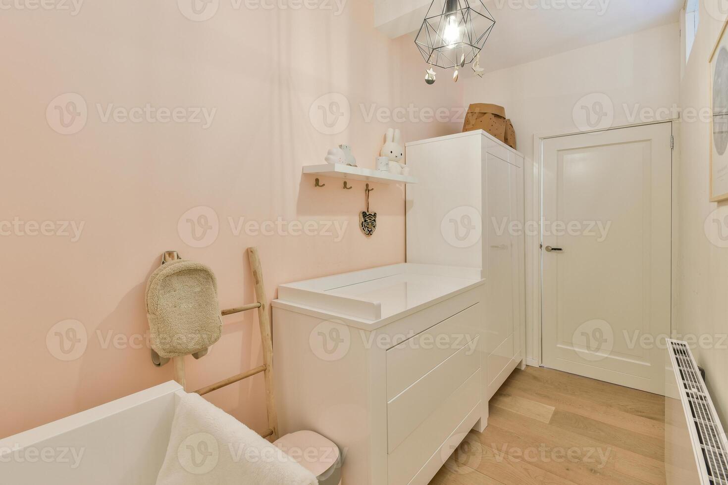 A bathroom with a pink wall and wooden floors photo