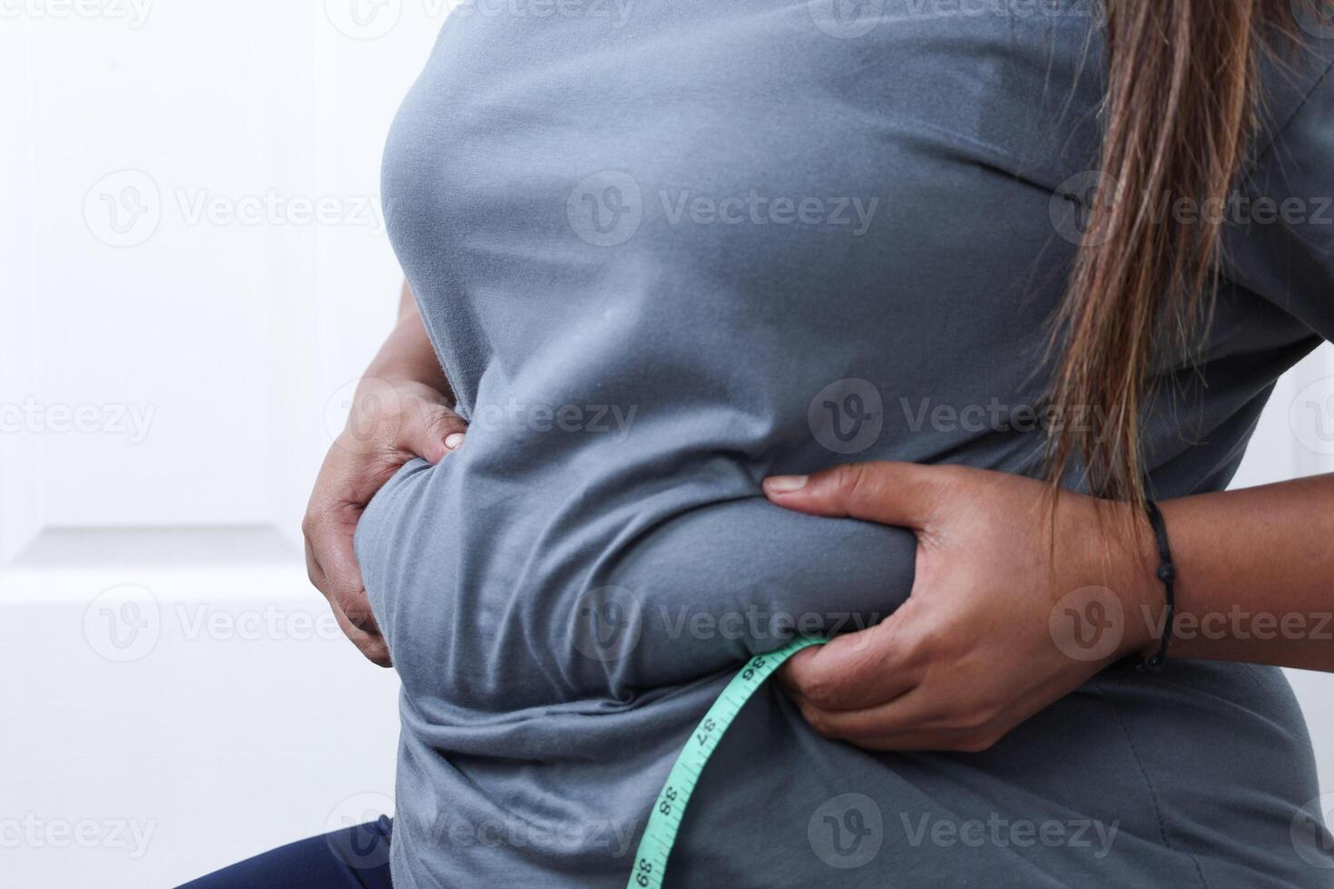 Obese Woman Hand Holding Excessive Belly Fat with Measure Tape photo