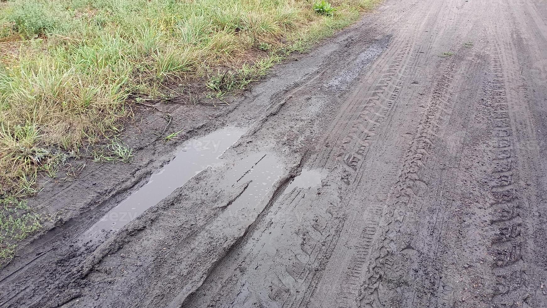 A muddy road with puddles of water on it The road is dirty and wet photo