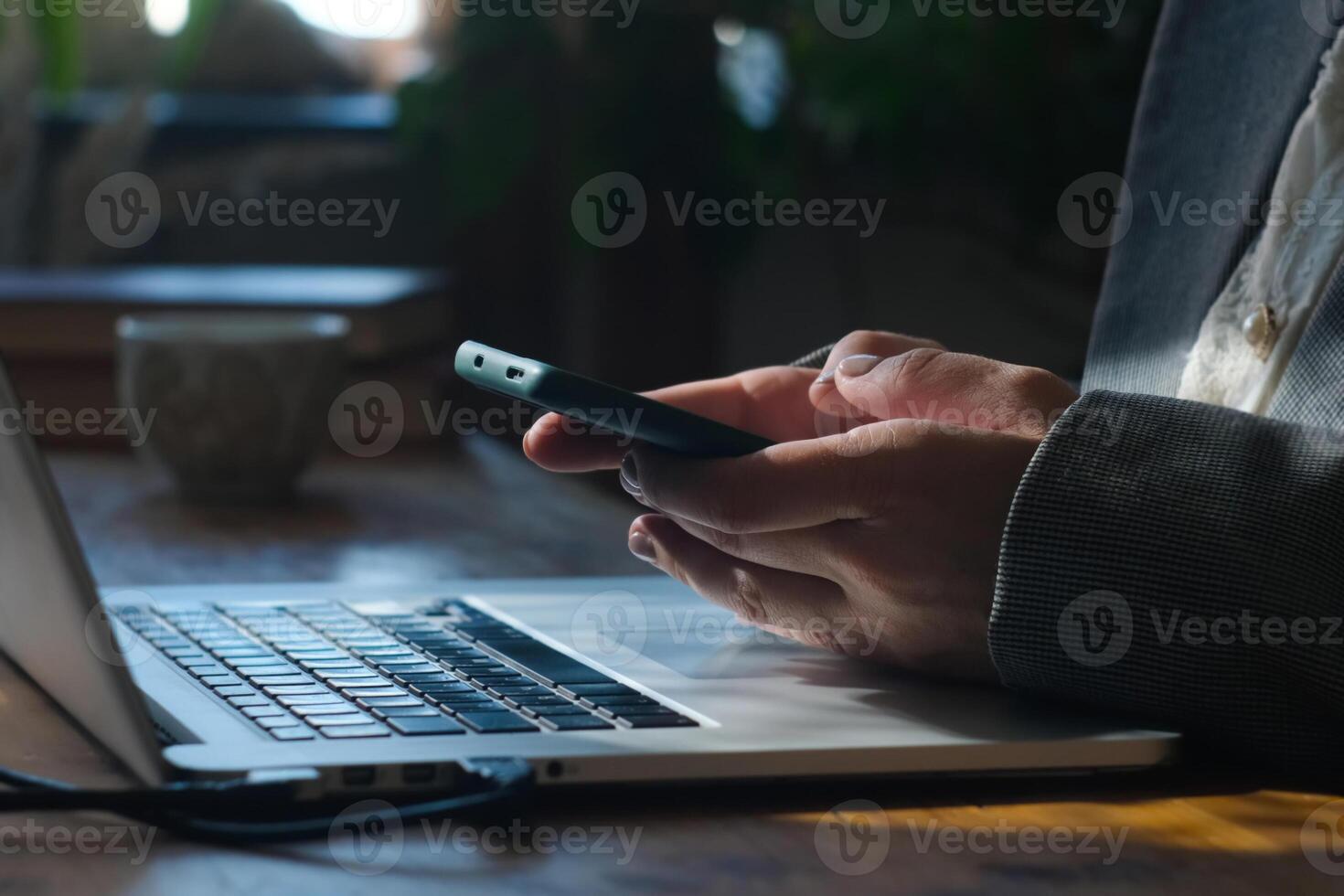 Woman holding mobile phone in her hands. Person browsing internet using smartphone at desk. photo