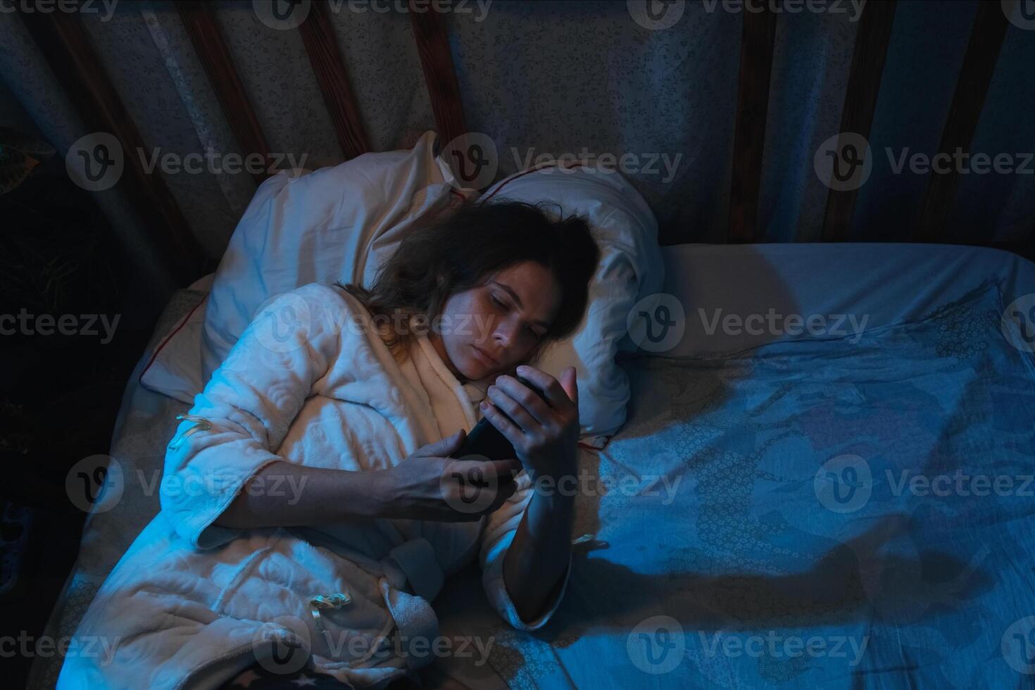Insomnia. Person cannot fall asleep, using smartphone lying in bed at night. photo