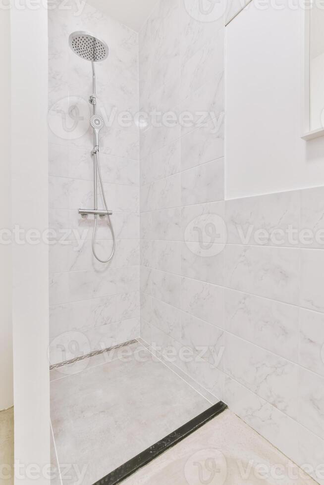 A shower with a white marble floor and a shower head photo