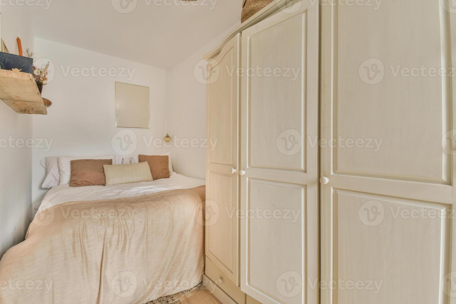 A small bedroom with a bed and a wardrobe photo
