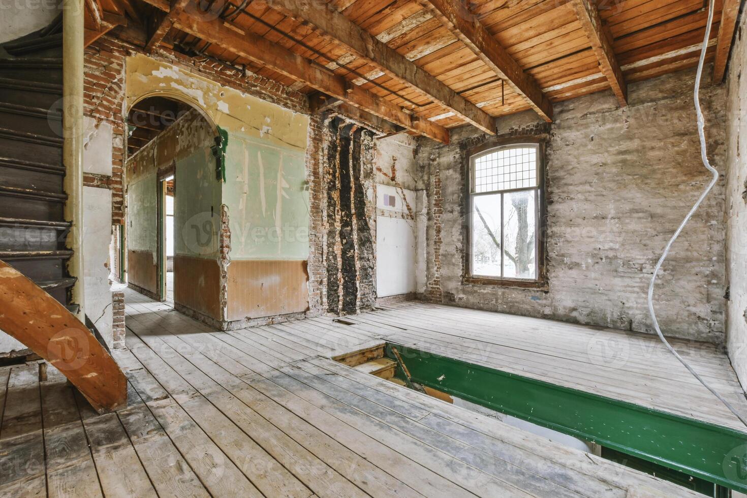 An empty room with wood floors and a staircase photo