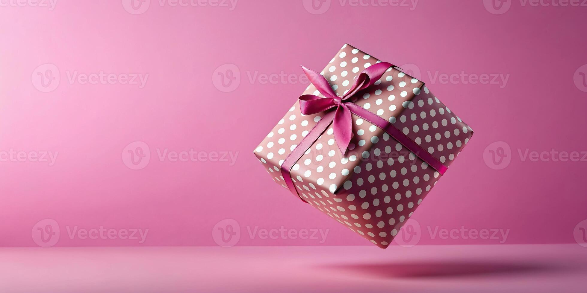 Polka dot gift box with ribbon floating in mid air against a pink background, ribbon, floating, falling, levitation, macro, pink background photo