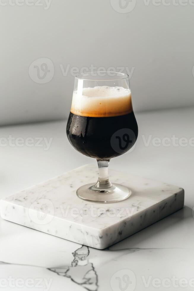A glass of dark beer sitting on a marble counter photo