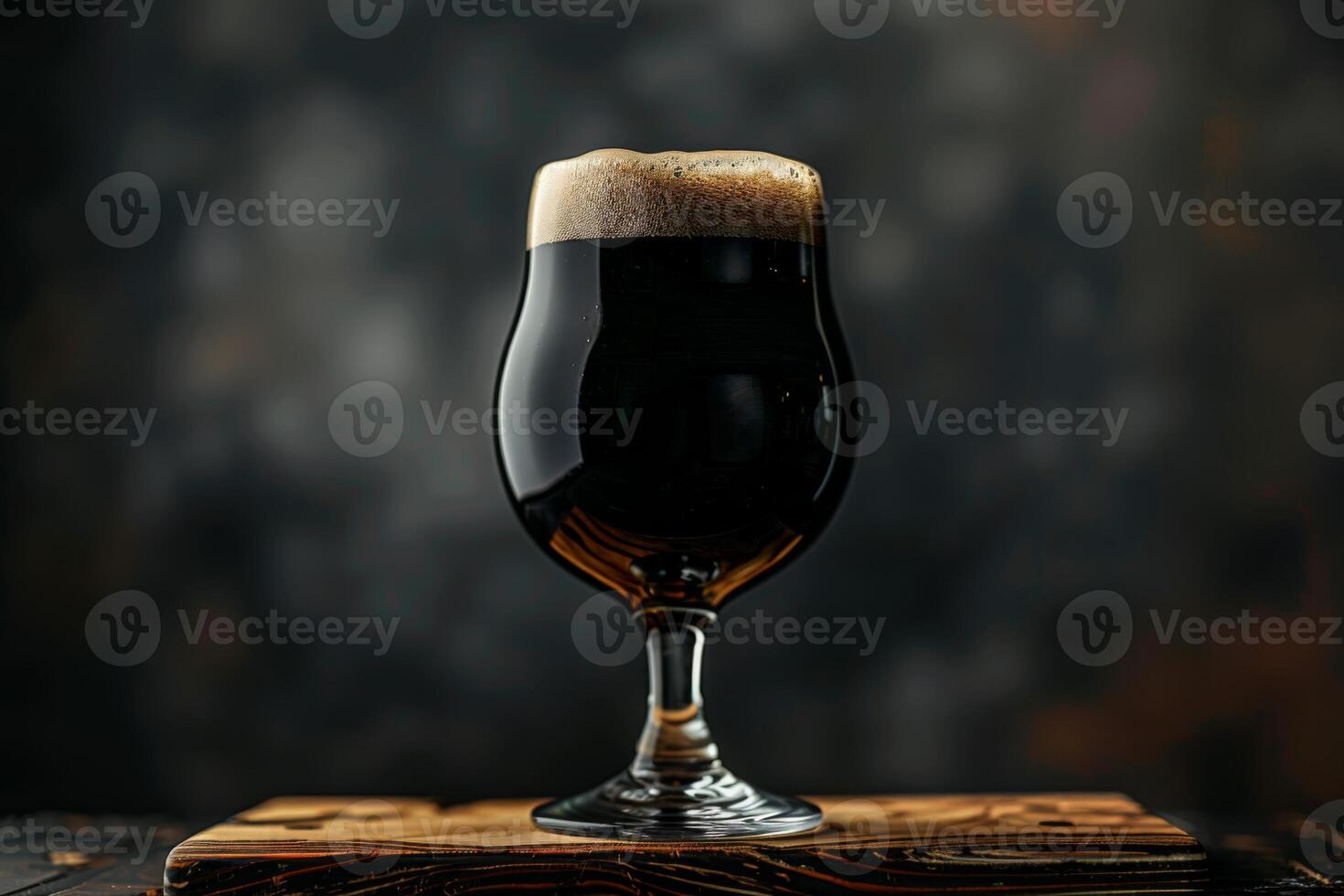 A glass of dark beer sitting on a wooden board photo