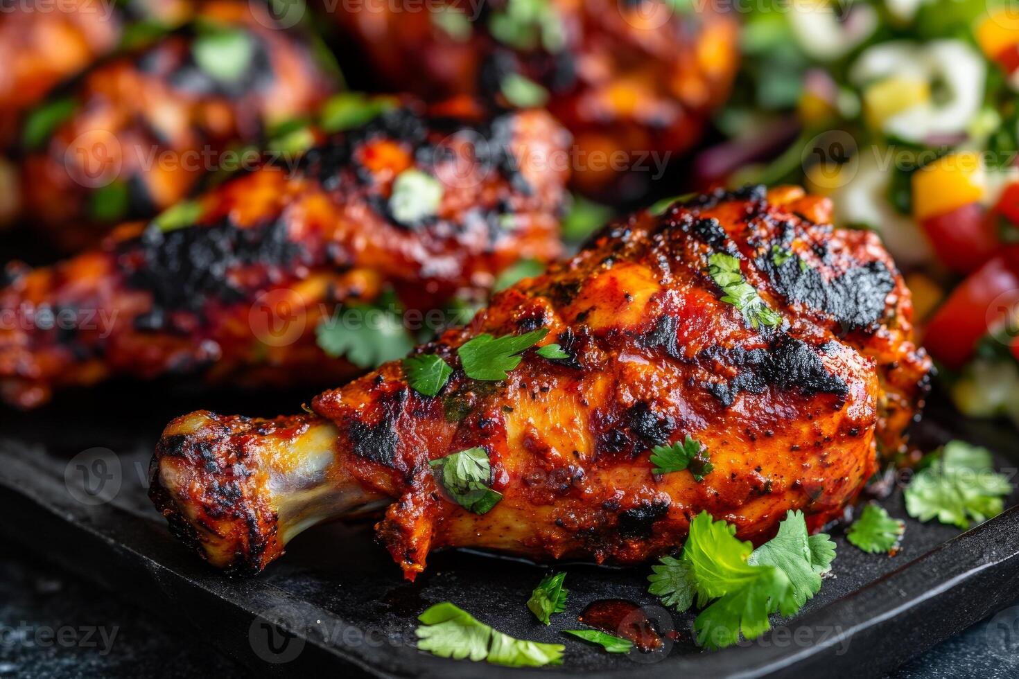 Grilled chicken wings with vegetables on a black tray photo