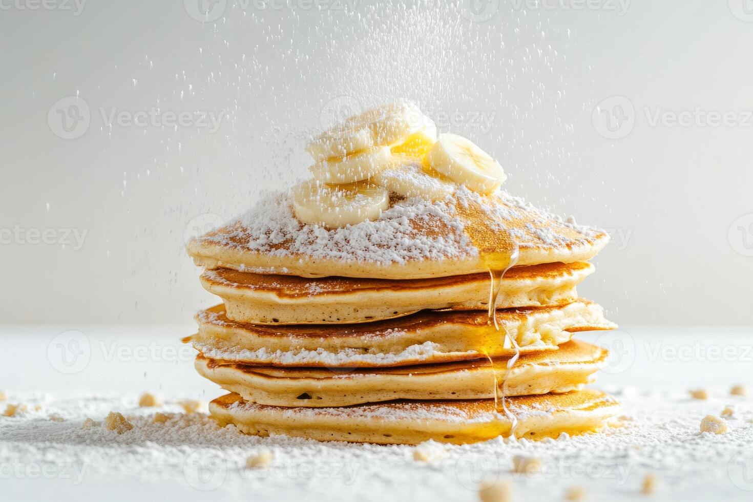 A stack of pancakes with powdered sugar and bananas photo