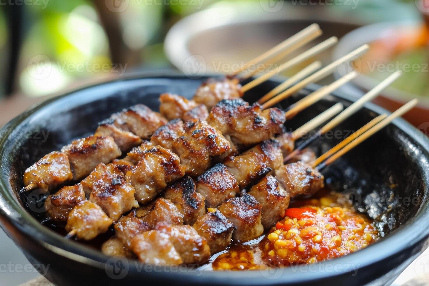 A bowl of meat on skewers with sauce photo