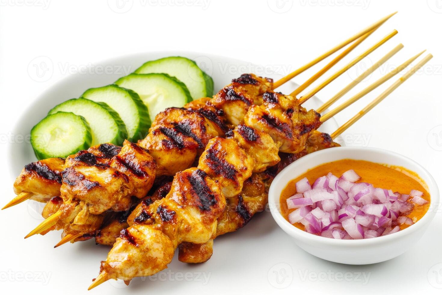 Thai chicken satay on a white plate with cucumber and onion photo