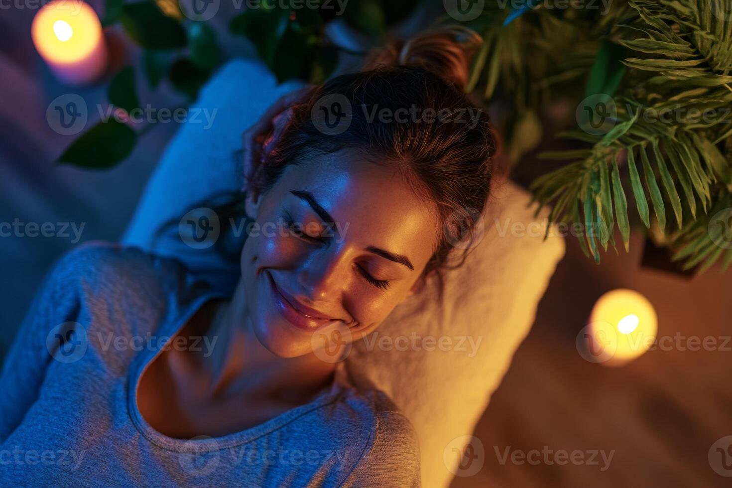 A woman is smiling while laying on a bed with candles photo