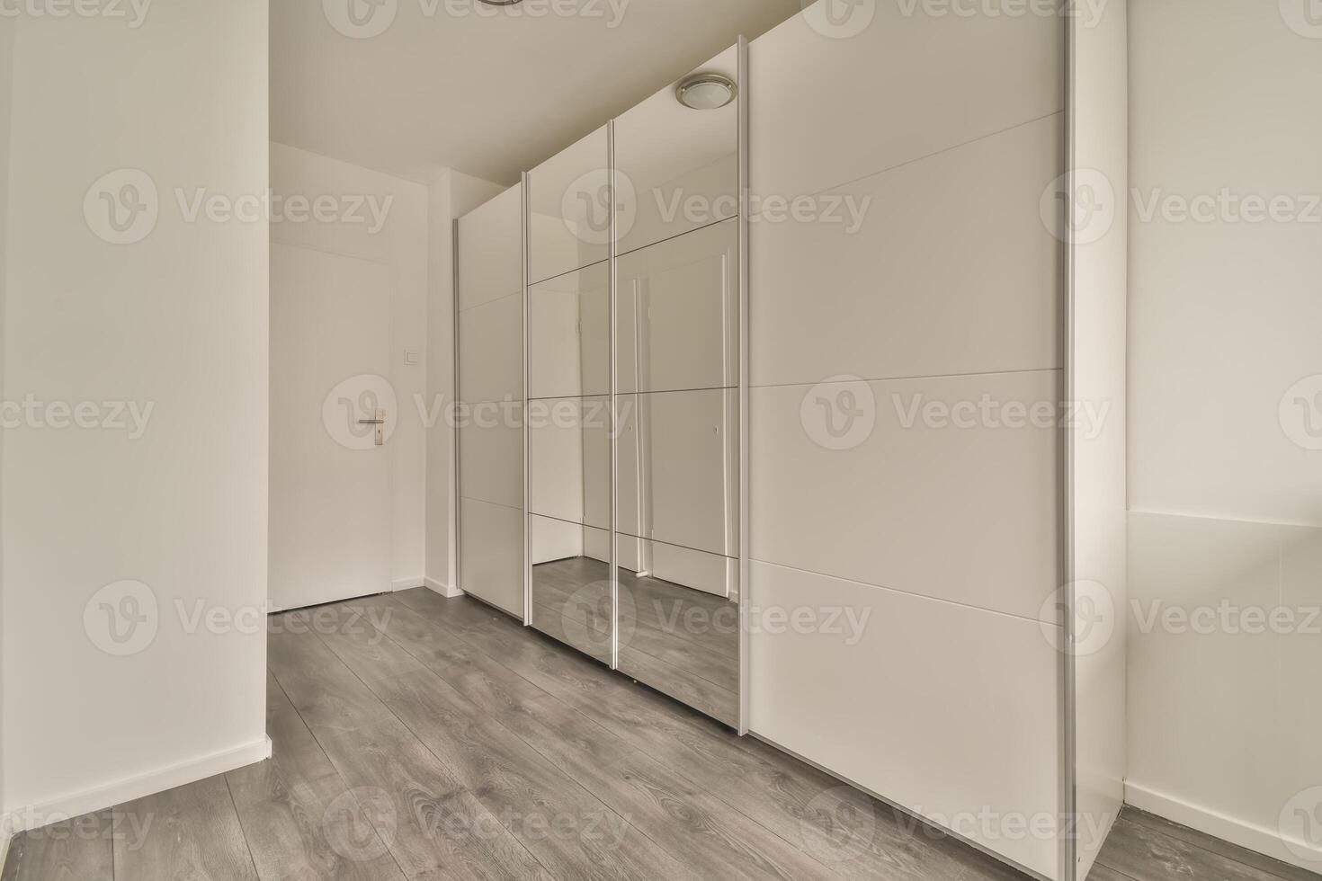 A white closet with mirrored doors and wooden floors photo