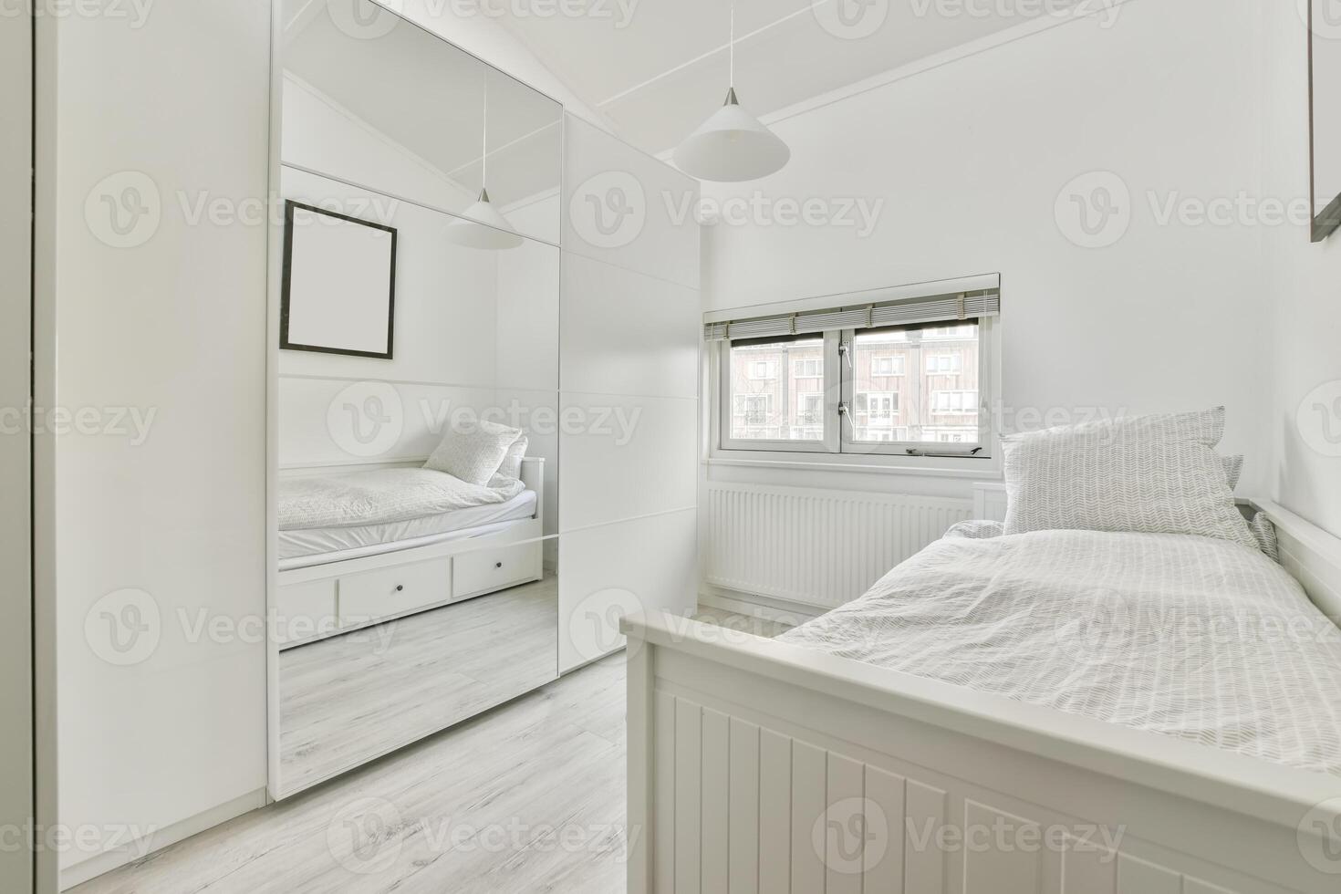 A small white bedroom with a bed and a mirror photo