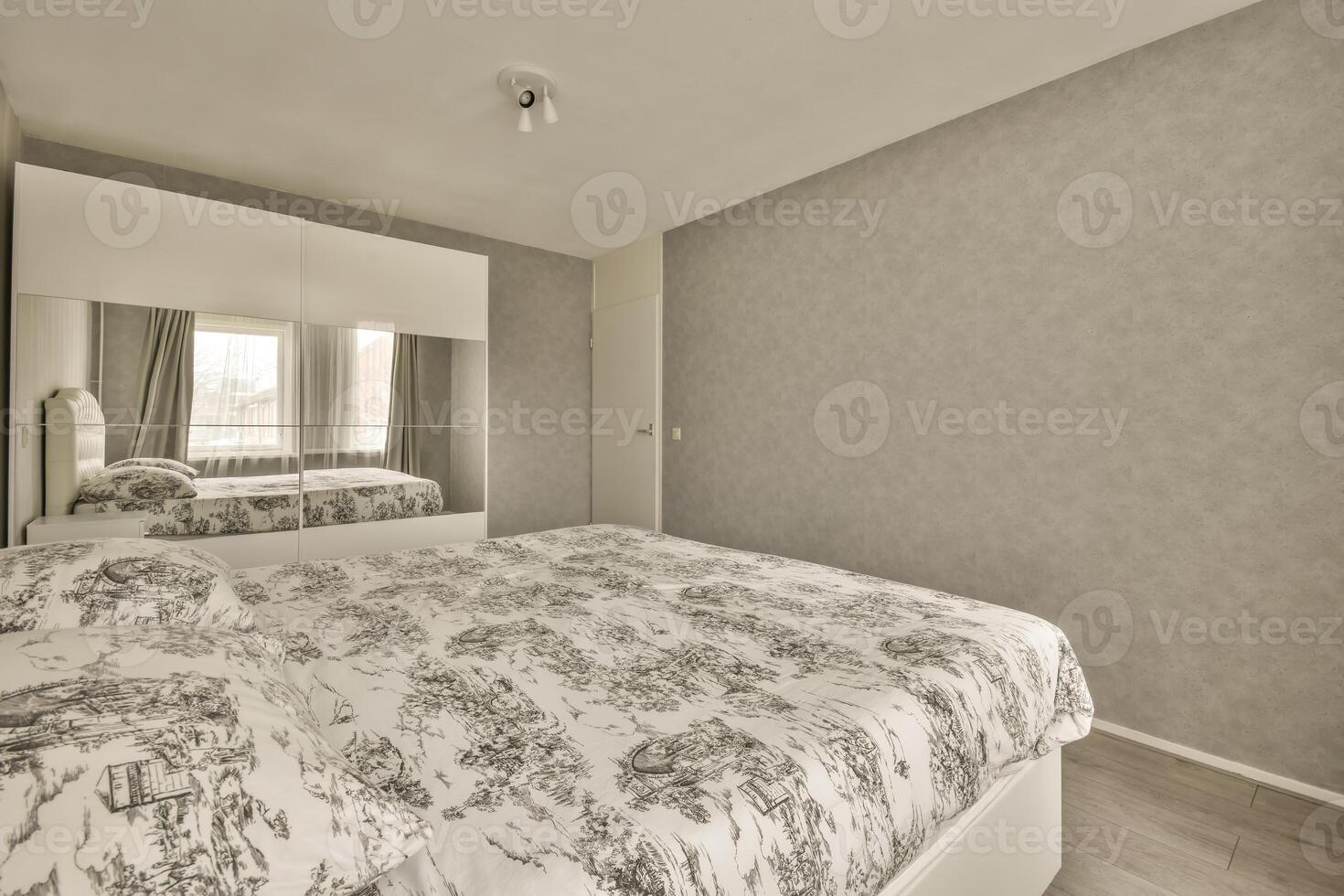 A bedroom with a bed, a mirror and a wall photo