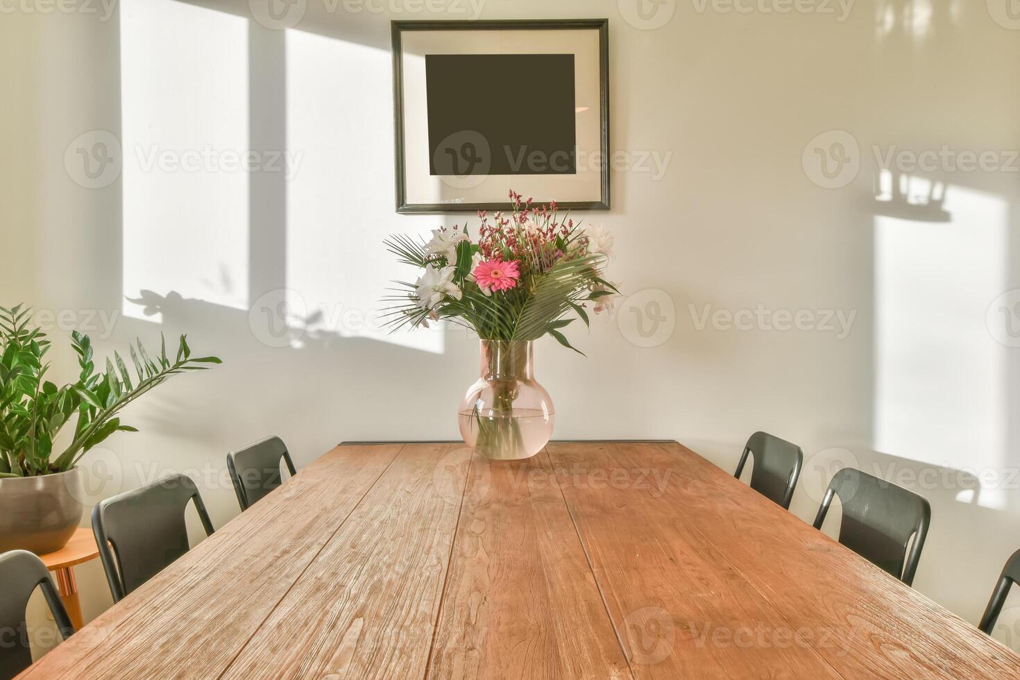A wooden table with black chairs and a vase of flowers photo