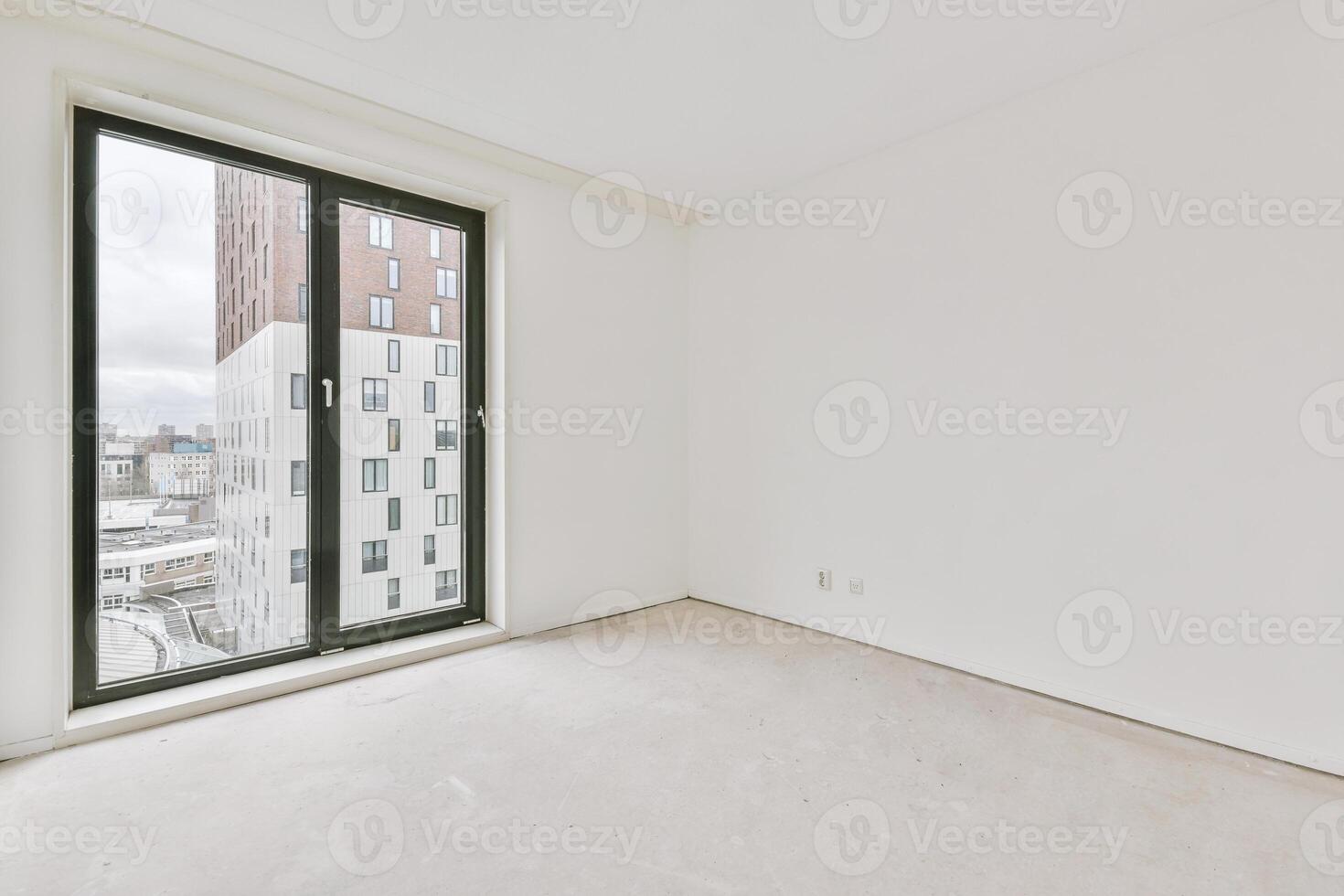 An empty room with a large window and white walls photo