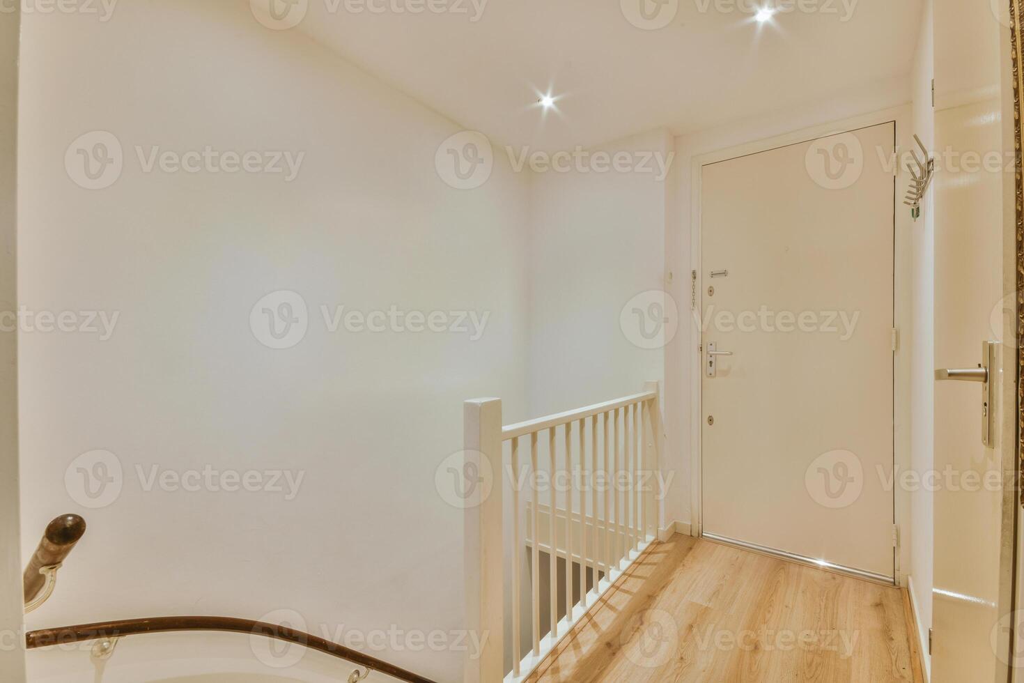 A hallway with a white door and a wooden floor photo