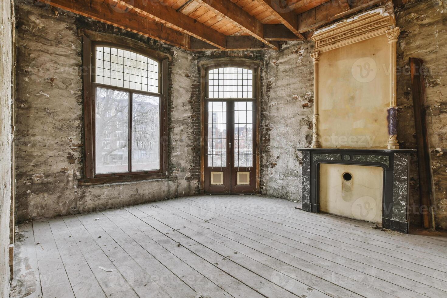 An empty room with a fireplace and windows photo