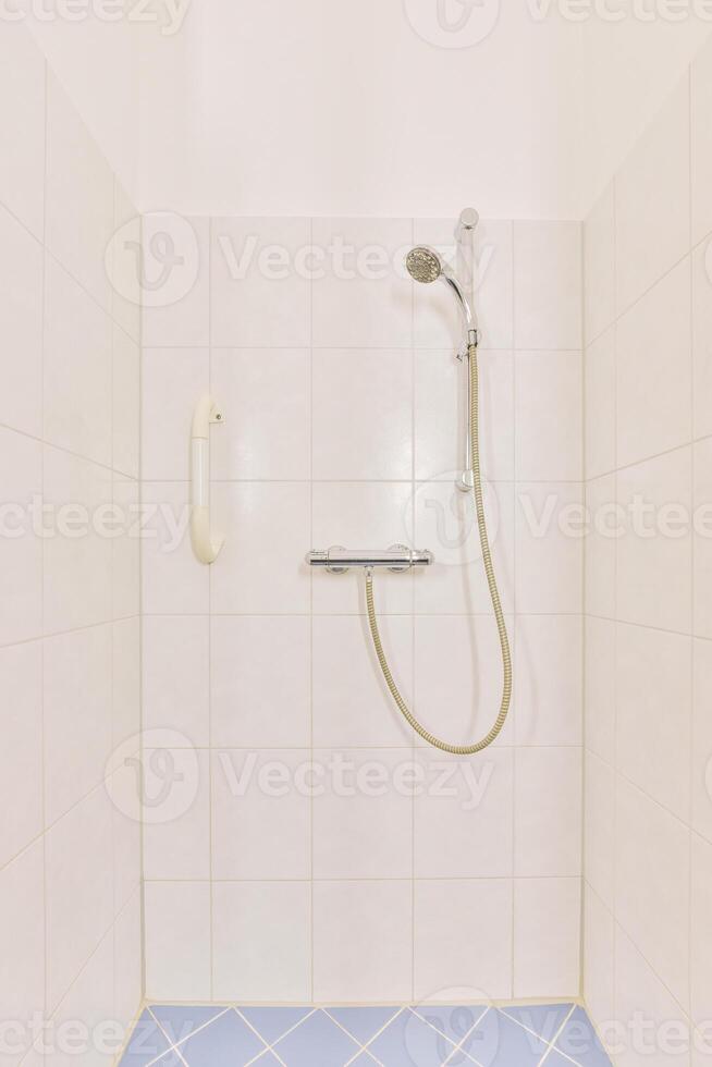 A shower with a blue tile floor and a shower head photo