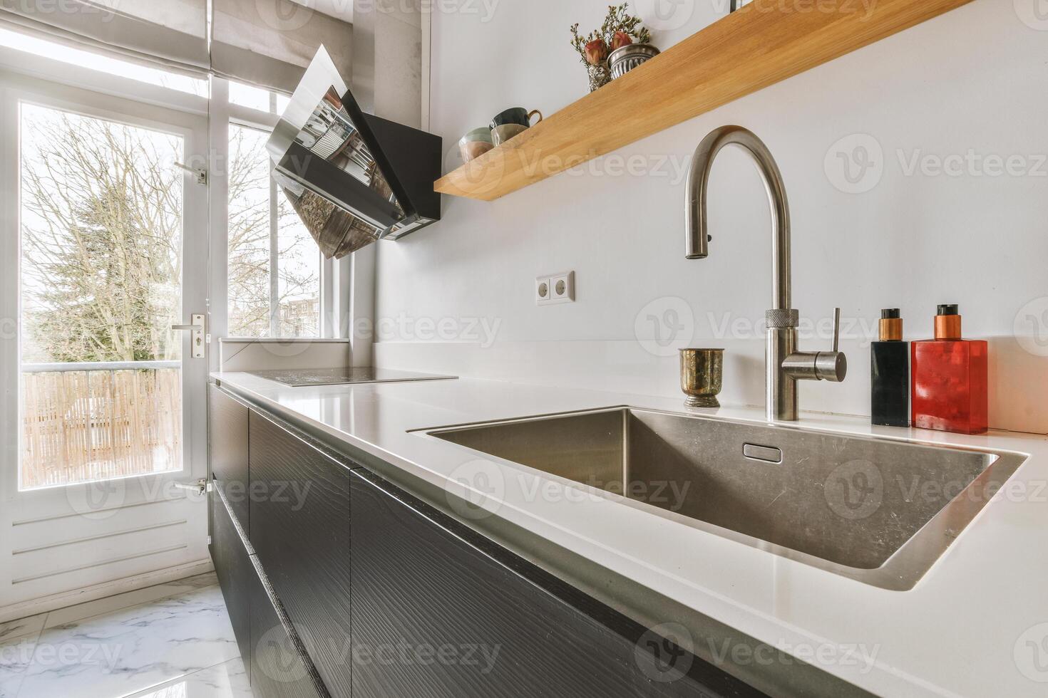 A kitchen with a sink and a wooden shelf photo