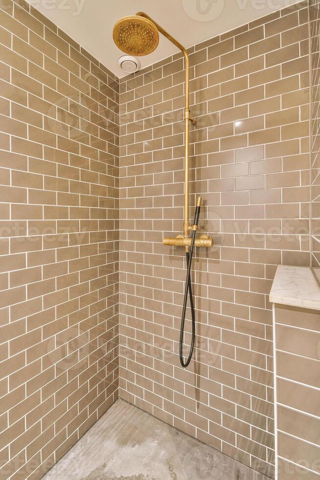 A shower with a gold shower head and a tiled floor photo