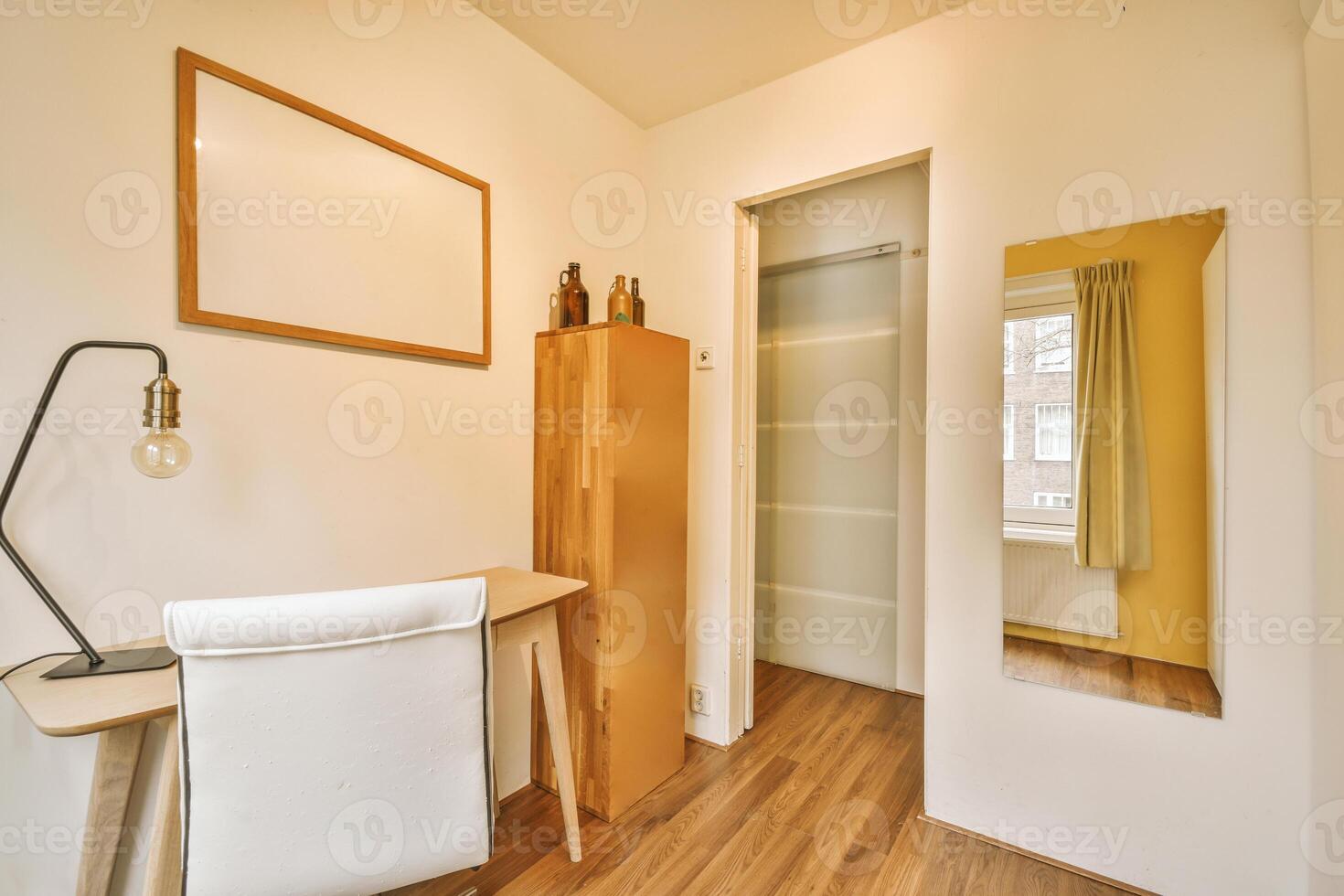A small room with a desk and a mirror photo