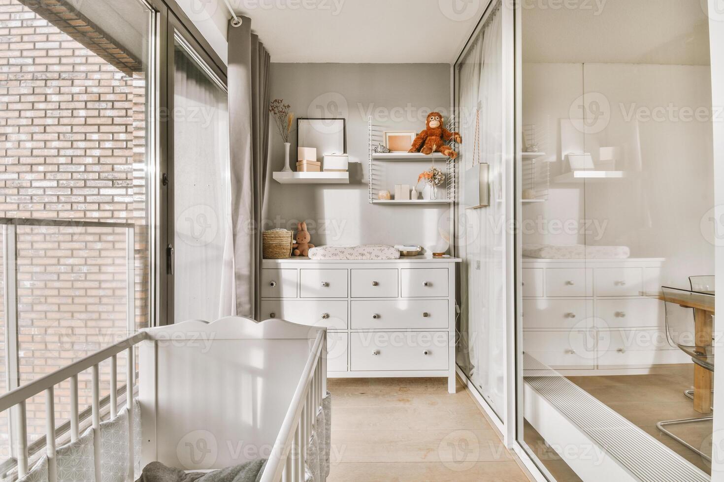 A white nursery with a crib, dresser and mirror photo
