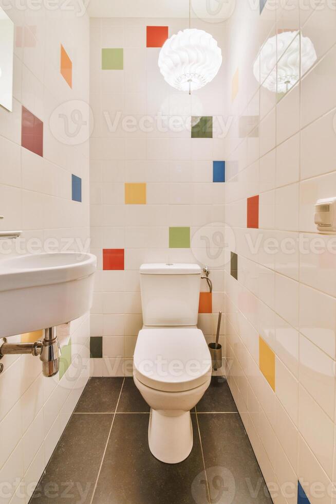 A bathroom with a white toilet and a colorful tile wall photo