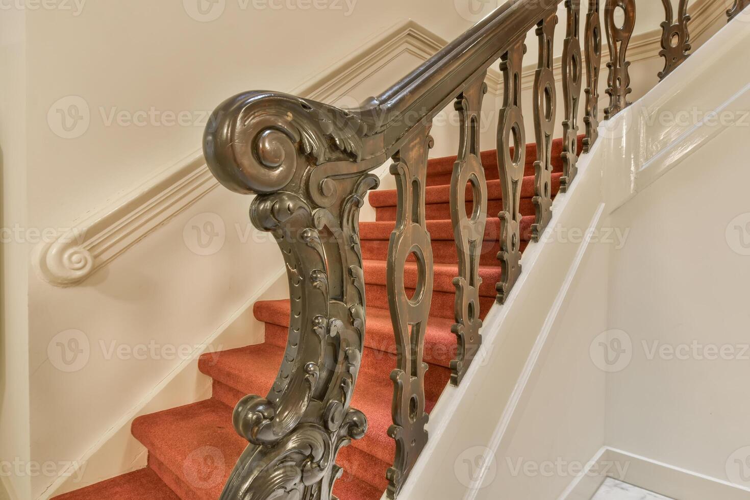 A staircase with a red carpet and white walls photo