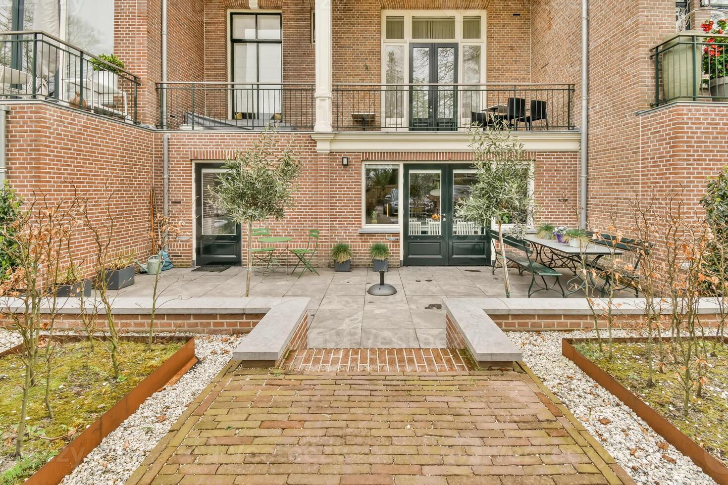 A brick patio with plants and a brick walkway photo