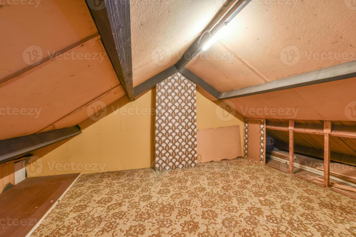 An attic with a carpeted floor and a wooden ceiling photo