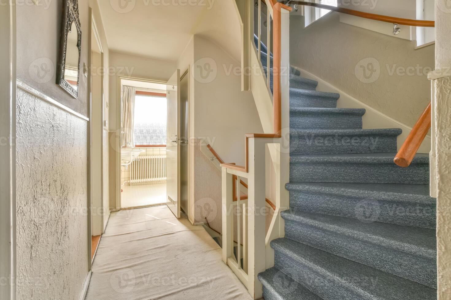 A hallway with stairs and a blue carpet photo