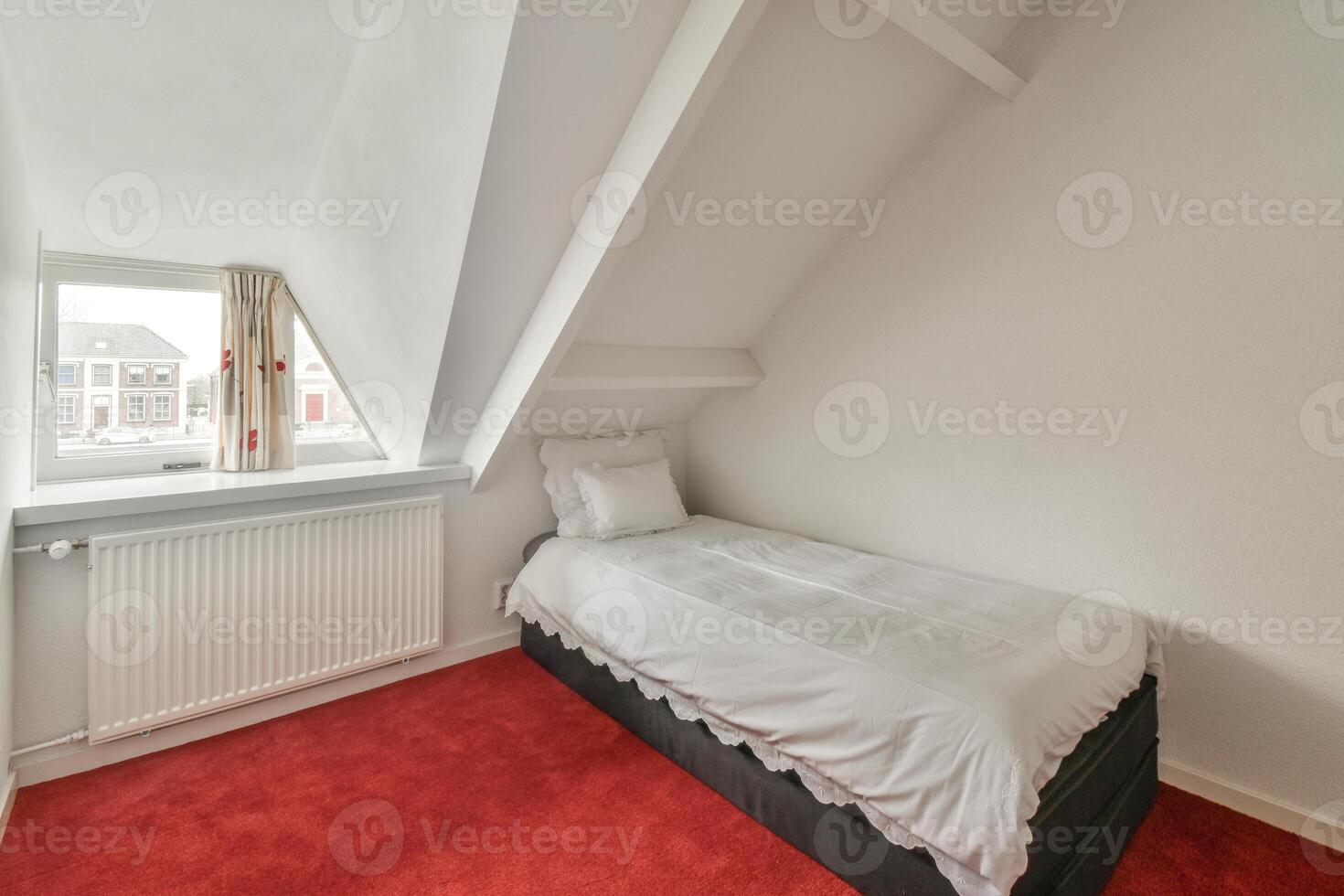 A small bedroom with a red carpet and a white bed photo