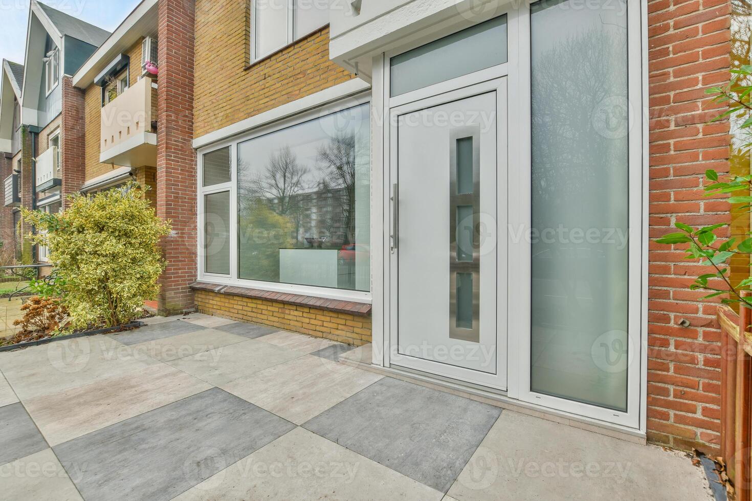 A white door is open in front of a brick house photo
