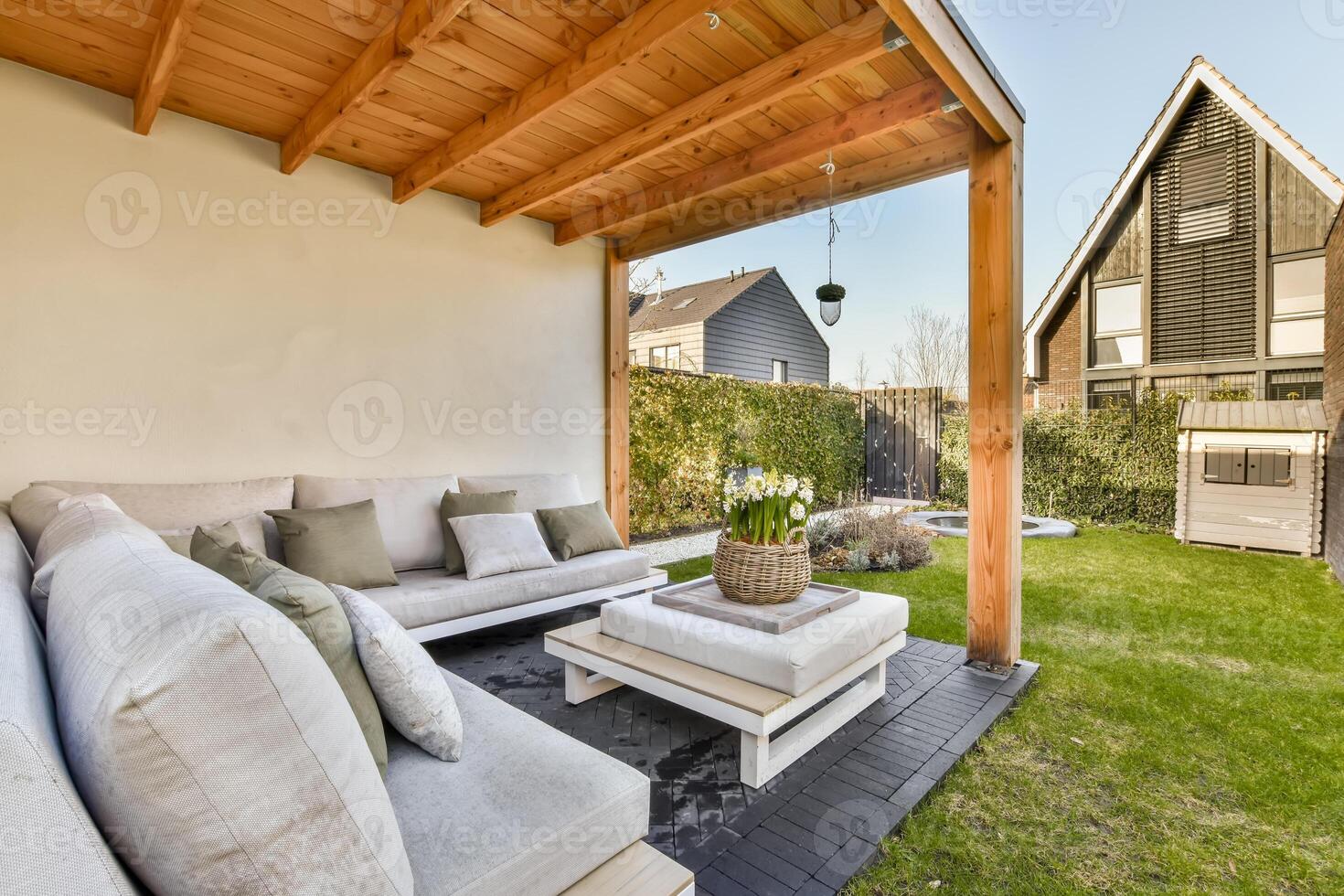 A backyard with a wooden covered patio and white furniture photo