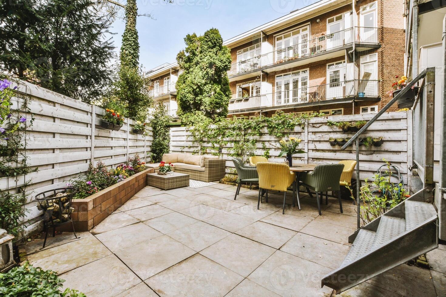 A patio with a table and chairs in front of a building photo