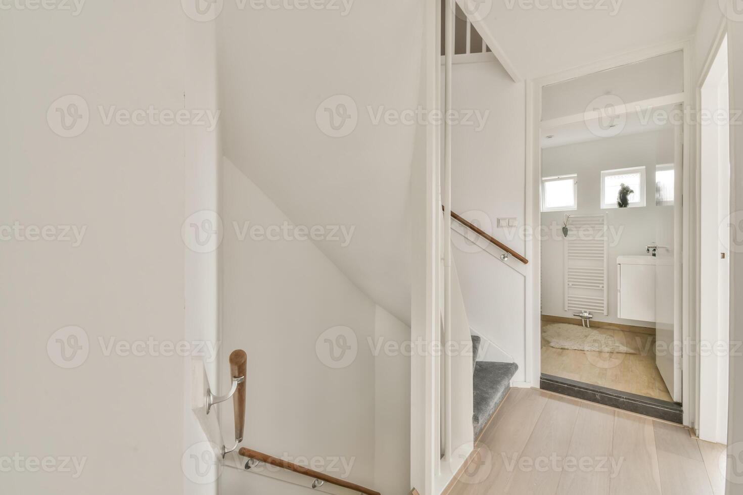 A hallway with a wooden floor and white walls photo