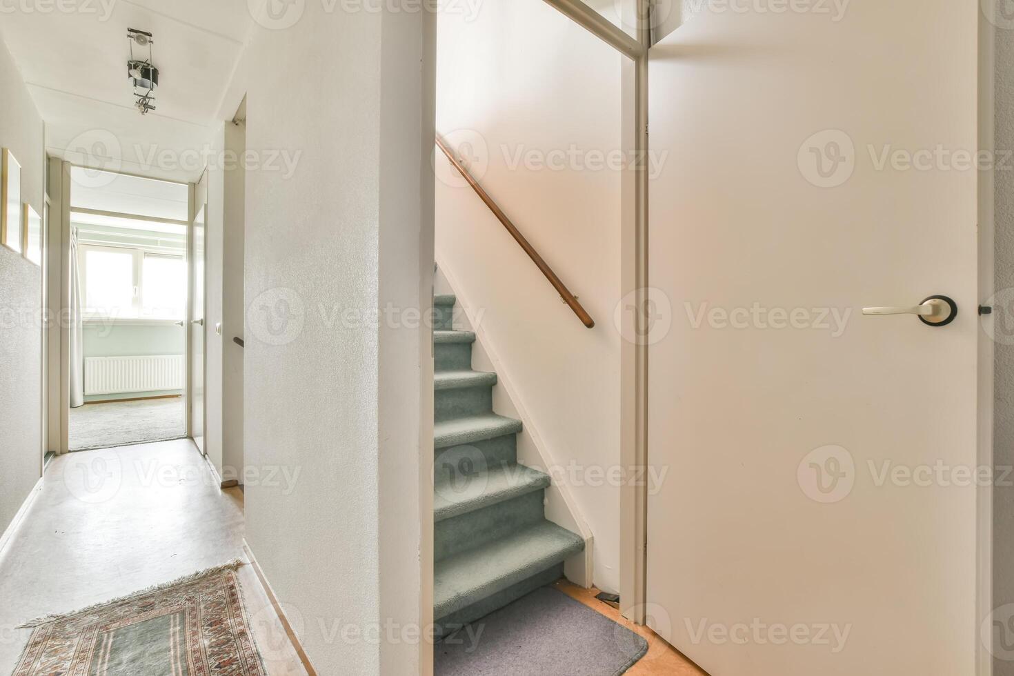 A hallway with a carpeted floor and a door photo